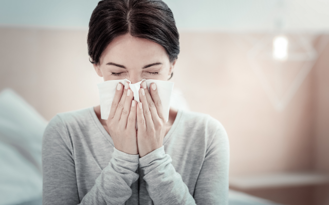 lady sneezing into tissue due to allergies